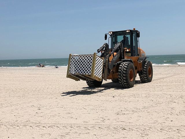 Ventnor front end loader moves a trash receptacle on the beach.