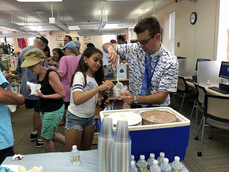 Library Director Ricky Gerhardt scoops some ice cream for a young library patron during the library's first anniversary celebration.