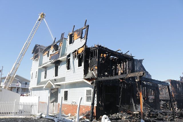 Water is sprayed on the smoldering remains of one of the duplexes.