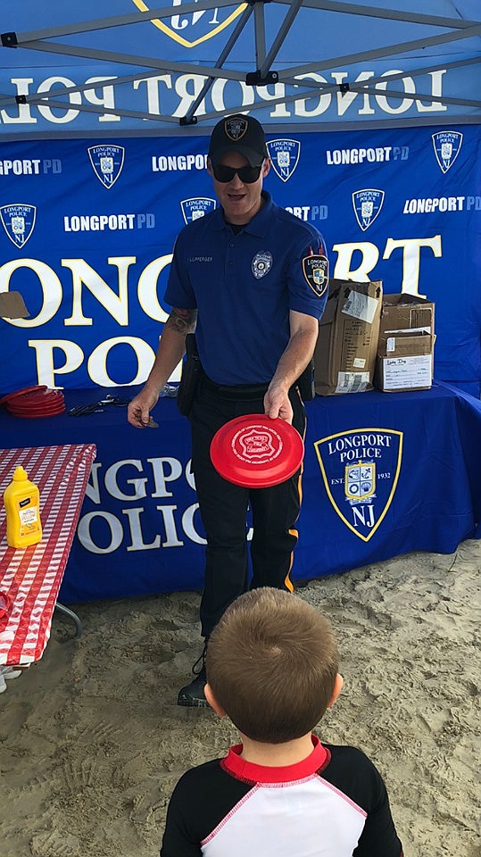 Longport Ptl. Frank Lupperger gives a frisbee to a youngster at the first in a series of community policing events.