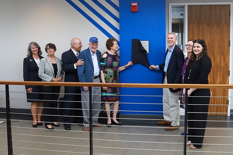 Myra Greenberg and son Paul unveil the plaque that names Room 313 at the Stockton University Academic Center for Myra and her husband Jerome.  Also pictured, from left, Claudine Keenan, dean of the Stockton School of Education; Johanna Johnson, chairwoman of the Stockton Foundation; Stockton President Harvey Kesselman; and Jerome Myra, Pau, Ellen and Amy Greenberg.