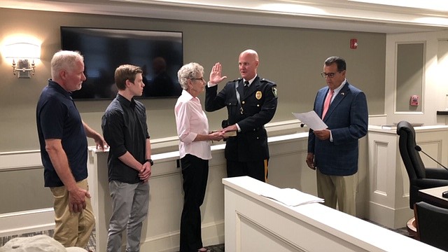 Matthew R. Hankinson takes the oath of office as Chief of the Margate Police Department administered by Margate Commissioner John Amodeo while his mother Elaine Hankinson holds the Bible.