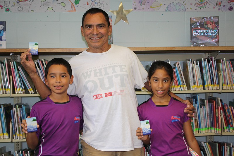 Christopher Barrera, 10, and Christine Barrera, 10, with Hernan Llerena, of Galloway Township, flaunt their library cards.