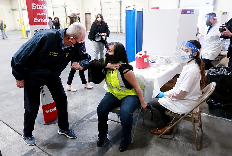 Photo by ED MURRAY/Gov. Phil Murphy bumps elbows with Elaine Lew before she receives the Johnson and Johnson vaccine. Members of the International Longshoremen's Association (ILA), AFL-CIO were vaccinated at new Elizabeth Seaport vaccination site for port workers, in Elizabeth on  April 6.