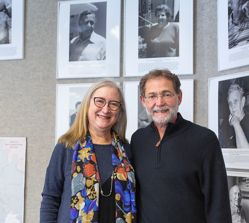 Barbara Harvis and Andrew Renny stand below photos of Andrew's parents, Marcell and Catherine Renny, Holocaust survivors whose stories are included in the archives of the Sara and Sam Schoffer Holocaust Resource Center at Stockton University. (Photo by Bernard DeLury/Stockton University