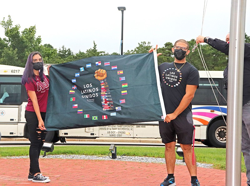 tudents from Los Latinos Unidos at Stockton University raise the flag at the Arts & Sciences Building circle to celebrate Hispanic Heritage Month in September 2021. (Photo by Stockton University)