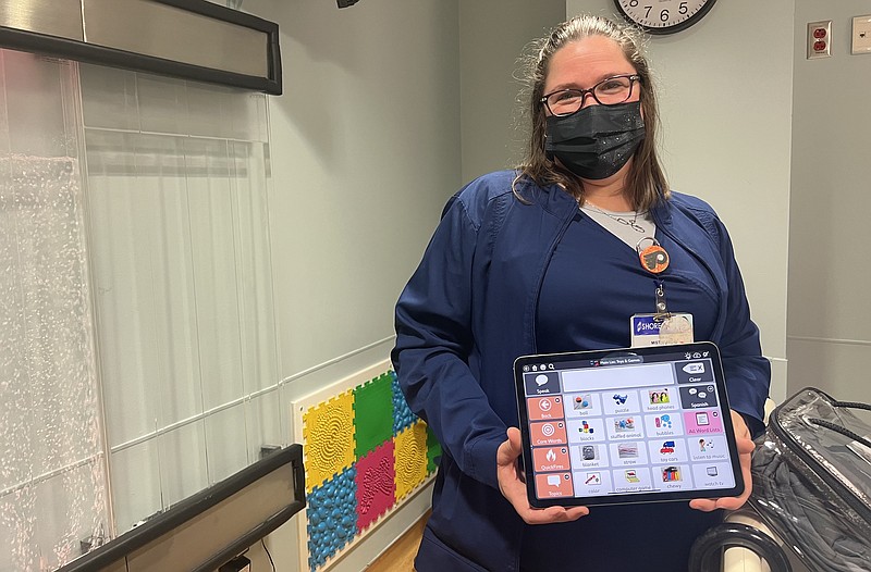 Provided/Shore Pediatric Care Center nurse Misti Martin with a few of the tools in Shore's sensory friendly toolbox, including a tactile wall behind her, an iPad app for communicating with nonverbal children, a weighted blanket, and a remote control bubble wall. 