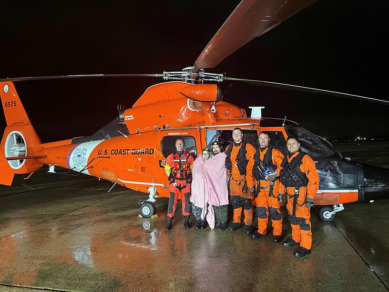 Courtesy U.S. Coat Guard/
An MH-65 Dolphin helicopter crew from Coast Guard Air Station Atlantic City, New Jersey, stands with two survivors May 6, after the aircrew rescued the couple. The two people were aboard a 33-foot sailing vessel when it grounded and overturned in heavy weather offshore from Little Egg Inlet.