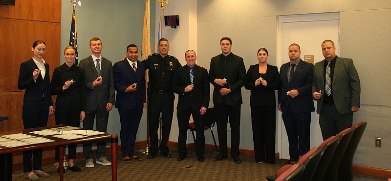 Nine new Sheriff's Officer recruits hold their star badges, with Atlantic County Sheriff Eric Scheffler.