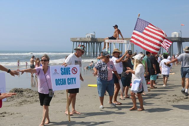 Anti-wind farm protesters hold hands along the beach in Ocean City.