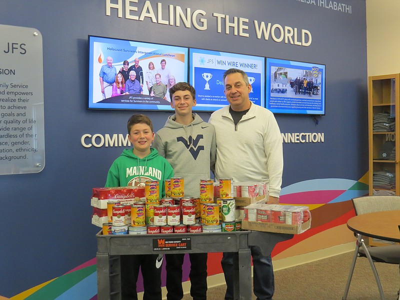 Provided/Michael, David, and JFS Board President Matthew Simpson help stock the agency's pantry with canned soup and vegetables. The agency provides an array of non-perishable foods as well as fresh fruits, vegetables, poultry, meats, frozen products and more to individuals and families in need. 