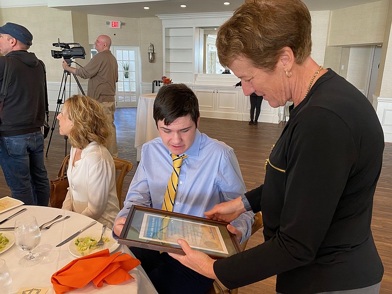 Brenda Scheffey admires her son Andrew's award. Andrew won the award for his work at The Other Lucy beach bar in 2023.