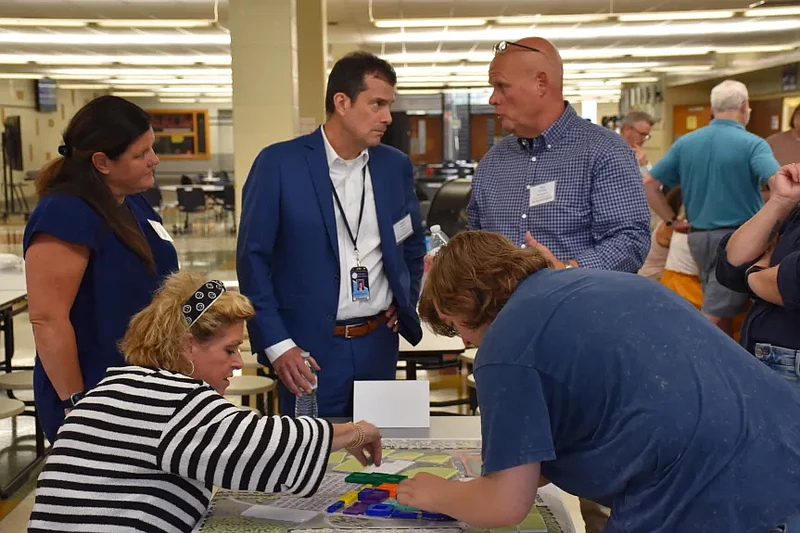 Towamencin supervisor Laura Smith, front left, and North Penn High School senior Nathan Schwing, front right, place plastic pieces meant to represent 