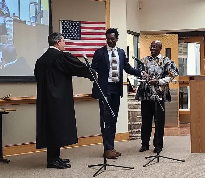 Towamencin NOPE founder Kofi Osei, center, shakes hands with District Judge Ed Levine after swearing his oath to be a township supervisor on Tuesday n