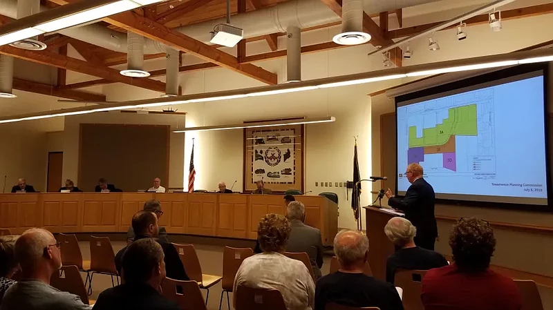 Attorney Carl Weiner, at podium, shows Towamencin’s supervisors an updated map of the township’s Village Overlay district, part of which developer PSD