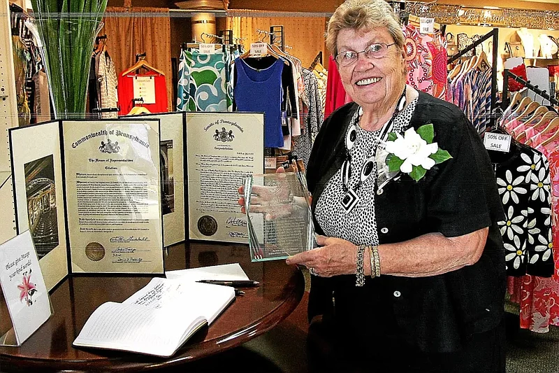 Margie Booz displays her Lifetime Achievement Award and resolutions from the Pennsylvania Senate and House of Representatives in her shop, Chantilly F