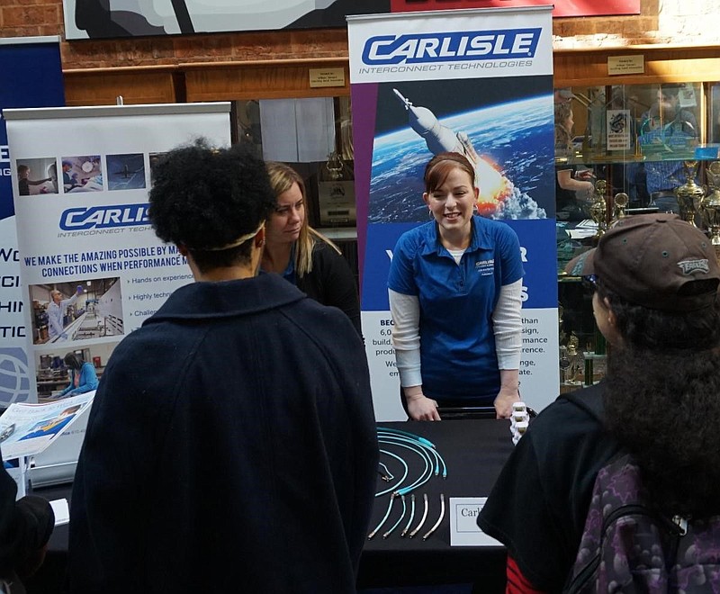 A representative from Carlisle Interconnect Technologies speaks with students during a career fair. 