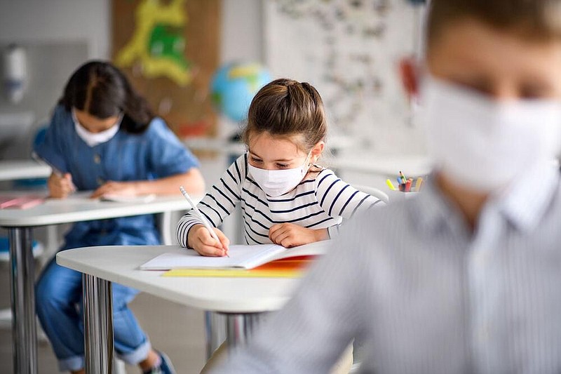 Stock image of students with face masks back at school taking a test. 