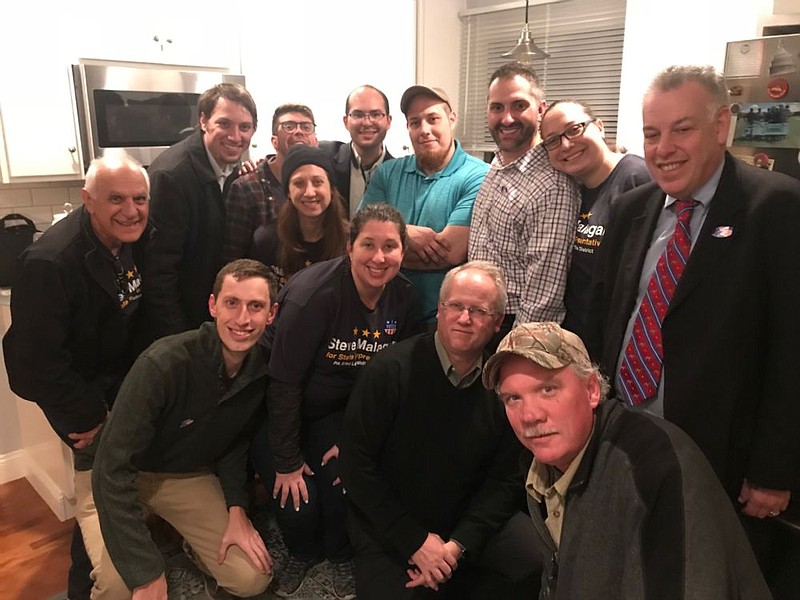 Malagari, in white checkered shirt, is surrounded by family, friends and campaign workers in his home following his win on Tuesday night. 