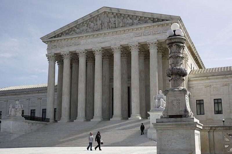 People walk outside the Supreme Court in Washington, Monday, March 16, 2020. 