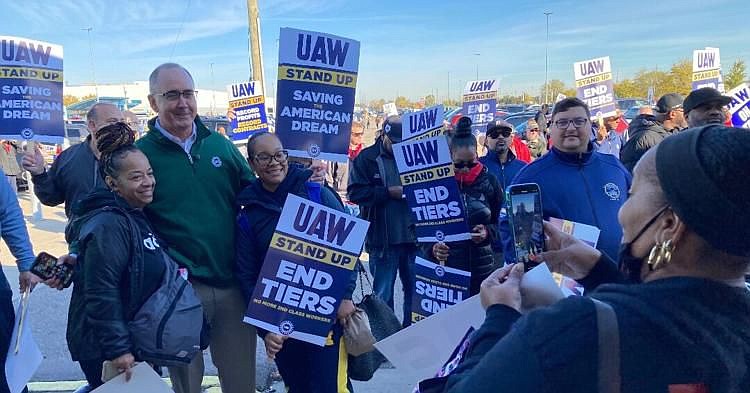 United Auto Worker Union President Shawn Fain stands alongside striking workers. 