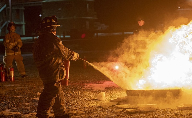 A firefighter puts out a fire during a training class. 