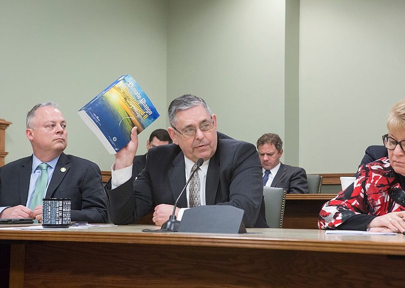 Rep. Cris Dush, R-Jefferson, holds up a compendium of climate research compiled by the Heartland Institute during a hearing on climate change. Dush an