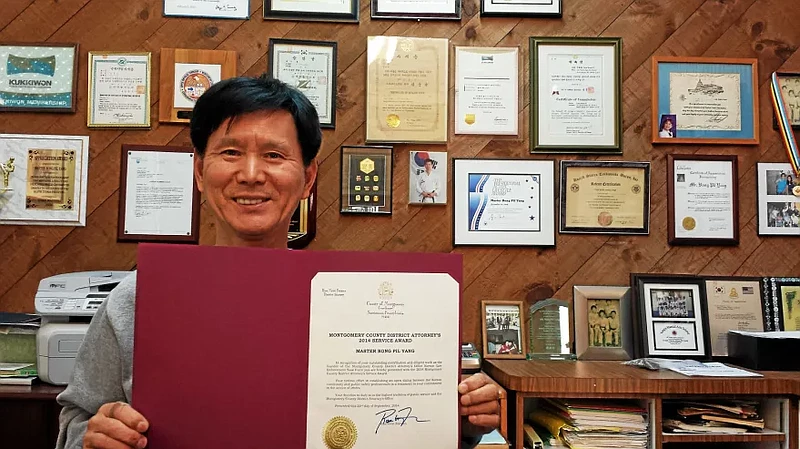 Master Bong Pil Yang of North Wales poses with an award from the Montgomery County District Attorney’s office at his martial arts studio in North Wale