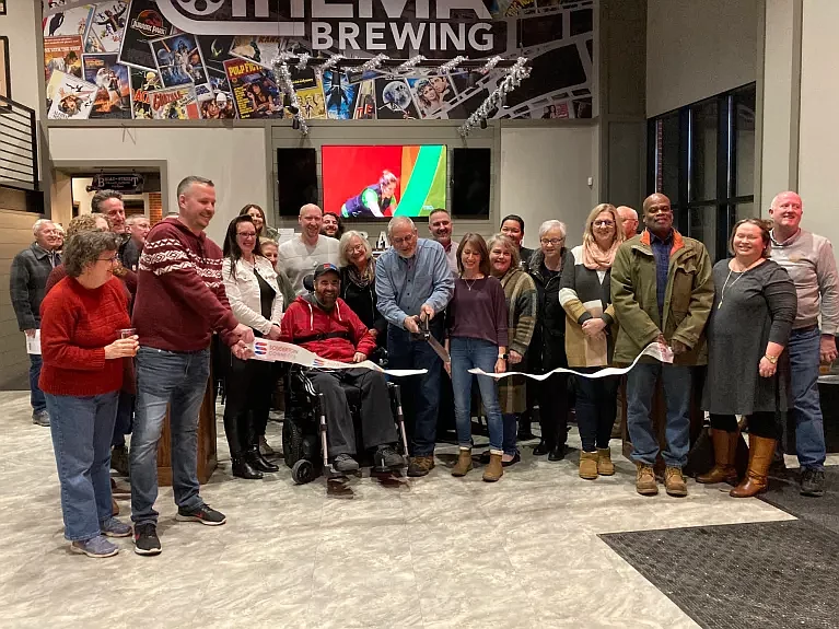 Broad Theater co-owner Charlie Crown cuts the ribbon at the grand opening ceremony of Cinema Brewery alongside co-owner Kevin Hoff, staff members and 