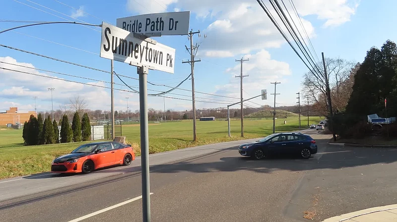 A car turns from Bridle Path Drive onto Sumneytown Pike, at an intersection where a new driveway entrance to North Penn High School could be added as 