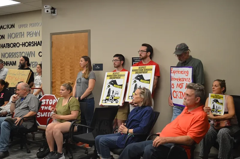 Attendees of a June 6, 2023 Norristown council meeting hold signs related to homeless encampments in Norristown. 