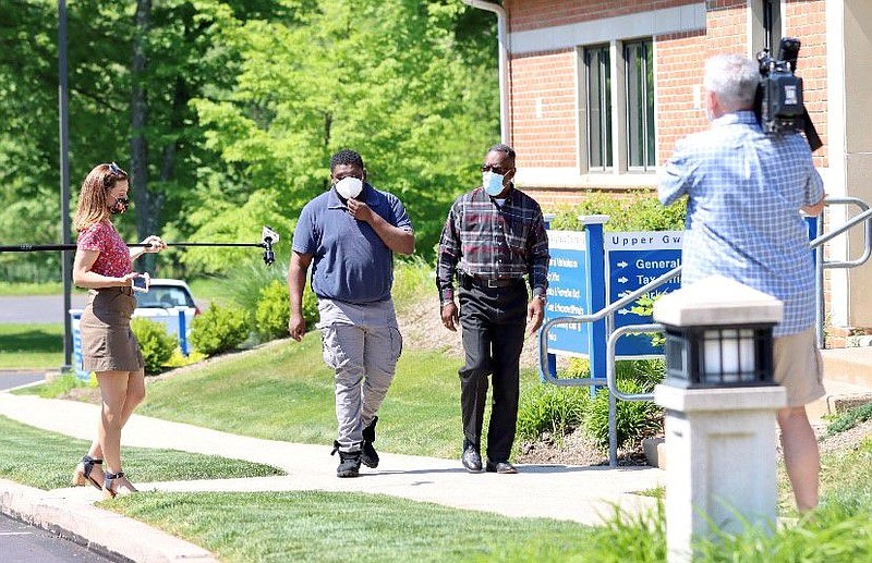 NBC 10’s Deanna Durante, left, questions 25-year-old Kashaan Moses, center left, as he turns himself in to the Upper Gwynedd Police Department on May 