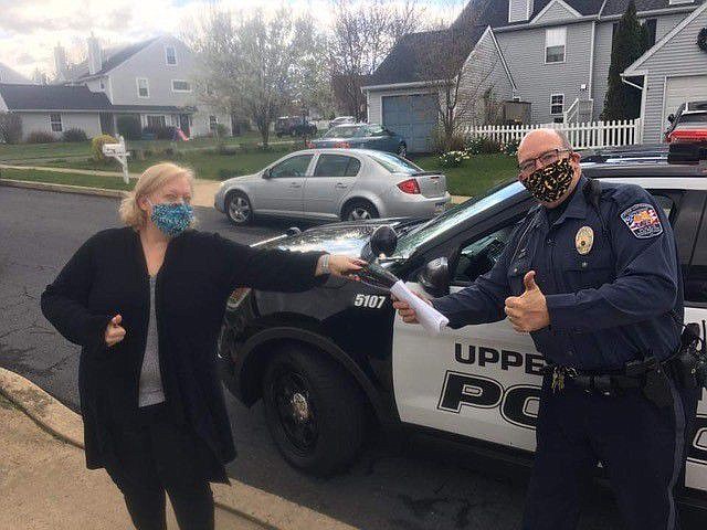 Towamencin DAR member Wendy Kelly hands off a batch of donated hand sewn face masks to Officer Fred Lynch of Upper Gwynedd Township Police Department.