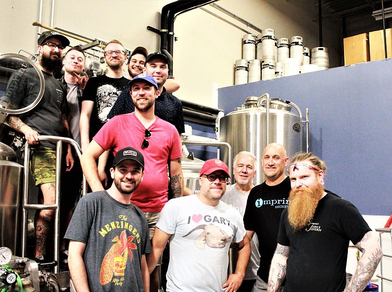 Members of Merit and Imprint Beer Co. take a break from brewing to pose for a photo. 