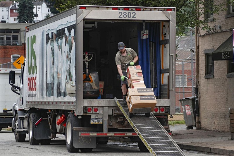 A food truck driver wheels a cart full of products for delivery to an establishment in Pittsburgh's Southside on the re-opening day for seated patrons