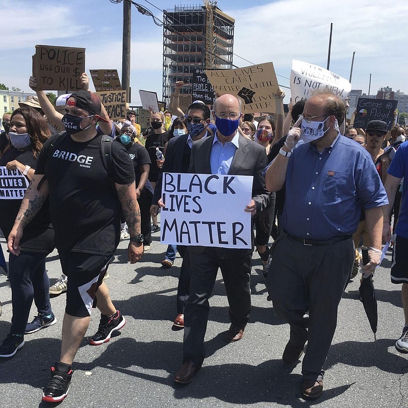 Gov. Tom Wolf, holds a "black lives matter" sign while walking alongside Harrisburg Mayor Eric Papenfuse, right, marches with demonstrators protesting