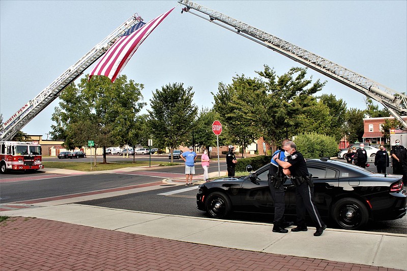 Officer James Owens, bottom right, hugs Lansdale Police Sgt. Rich Bubnis outside of Borough Hall on Tuesday morning. 