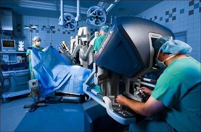 A surgeon controls the robot’s camera and instruments to perform an operation.