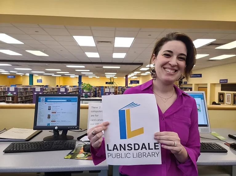 Lansdale resident and graphics designer Kim Moses poses with her new logo for the Lansdale Public Library, which won a library contest and will be rolled out at the library in the near future, on May 14 2024.