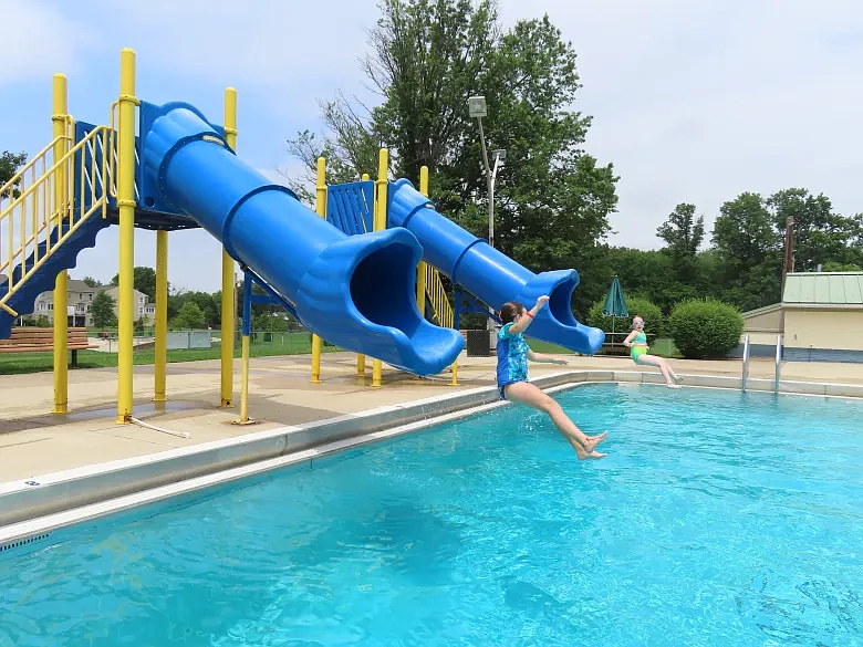 Katie, left, and Grace Quinn Lansdale catch air as they emerge from waterslides at the Fourth Street pool on Tuesday, July 13 2021.