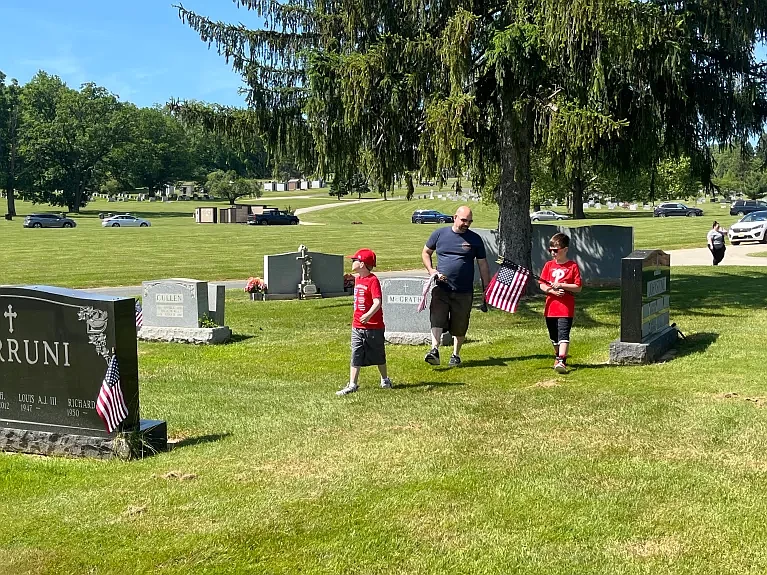 Michael Sasso, center, of Lansdale, walks through Calvary Cemetery with his sons, Julien, 8, and Michael, 10, helping to plant flags at the West Conshohocken cemetery ahead of Memorial Day in 2023. (Credit: Rachel Ravina / MediaNews Group)