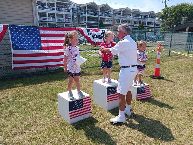 Addison Esposito, 3, is awarded one of her gold medals by Bill Murphy, commodore of the Yacht Club of Sea Isle City.