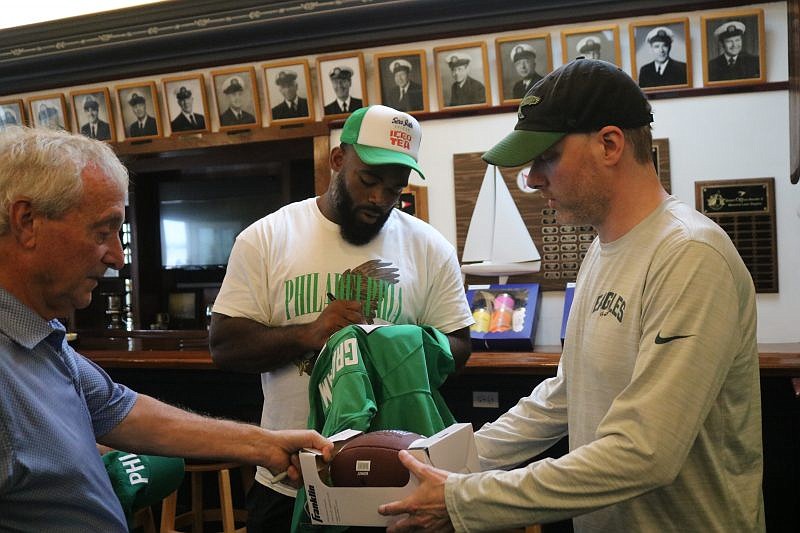 Brandon Graham signs an Eagles Jersey and football for fans.