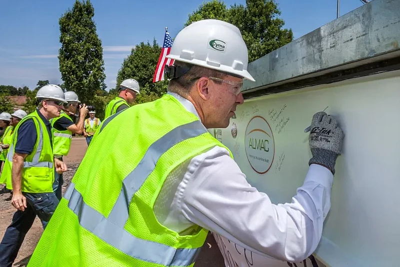 Almac Group marks the next phase of its 115,000 expansion project with a beam signing and “topping out” ceremony.