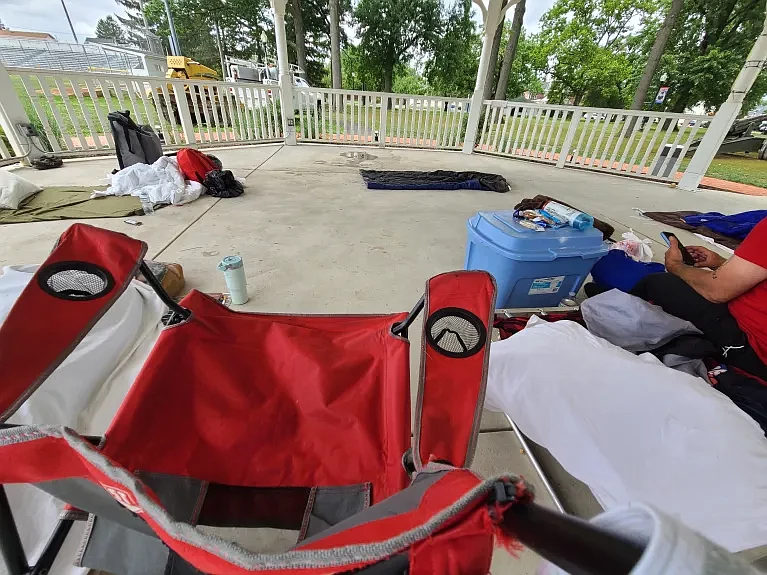 A man checks his phone while sitting on a cot inside the gazebo at Memorial Park in Lansdale on Tuesday, July 23 2024.