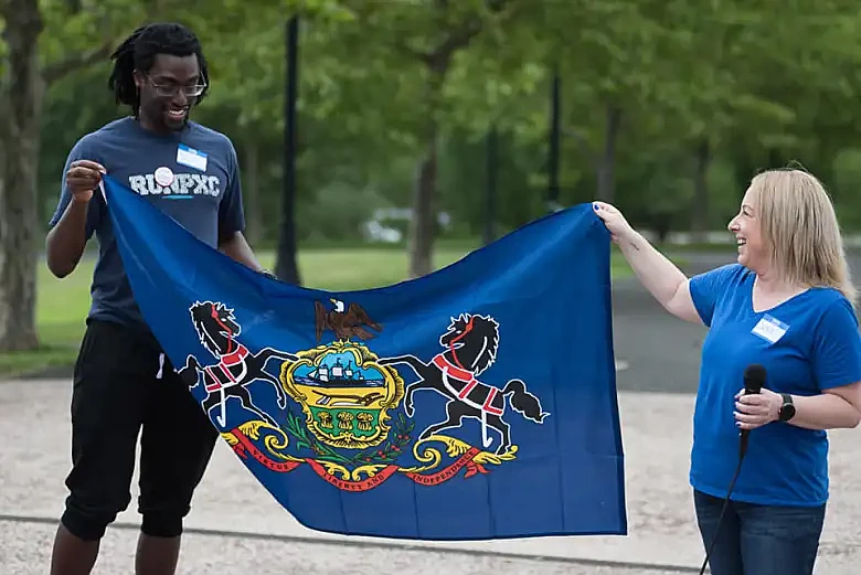 Towamencin residents Kofi Osei, left, and Jenn Foster hold a state flag after both spoke during Towamencin’s first “Charter Day” on July 1, 2023.