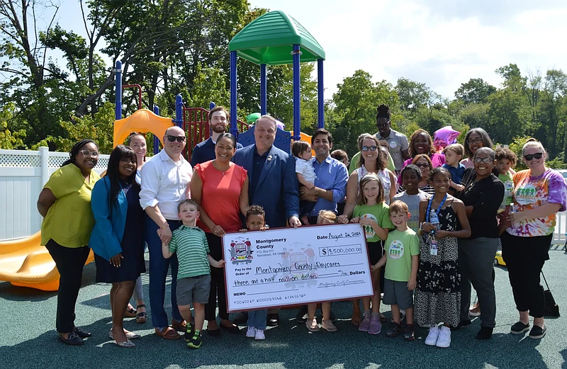 Montgomery County officials, staff, child care agency representatives, and children gather for a photo on Aug. 26, 2024 celebrating a check presentation at Kidz Konnect Childcare Center in Blue Bell, directing funds to a number of Montgomery County child care agencies through the Childcare Operation Recovery Program. (Rachel Ravina – MediaNews Group)