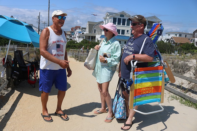 Sea Isle City beach tag checker Rocco Docimo talks with beachgoers Eileen and Tom MacDonald at the start of the holiday weekend.