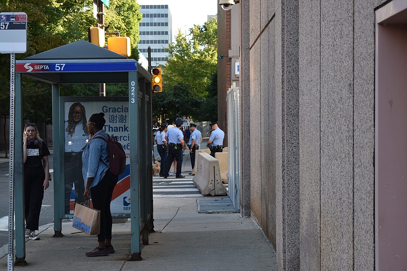 Philadelphia police wait in advance of Tuesday night's presidential debate as commuters also wait at a nearby bus stop.