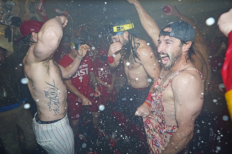 Sep 23, 2024; Philadelphia, Pennsylvania, USA; Philadelphia Phillies first baseman Bryce Harper (3), outfielder Brandon Marsh (16) and catcher Garrett Stubbs (21) celebrate the National League East Division title in the locker room after defeating the Chicago Cubsat Citizens Bank Park. Mandatory Credit: Eric Hartline-Imagn Images